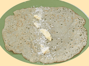 dessicated coconut and butter spread on  Appau/pancake, ready to be rolled and eaten